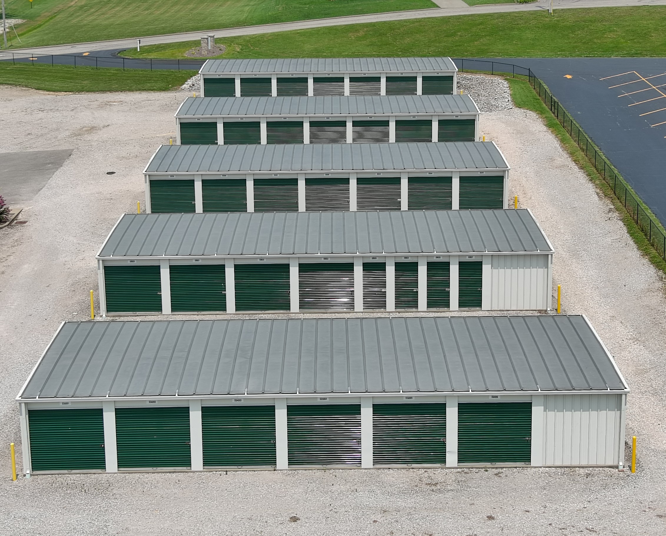 Accessible storage units with eye-catching green doors, complemented by broad driveways at Ferdinand's 1st St facility.